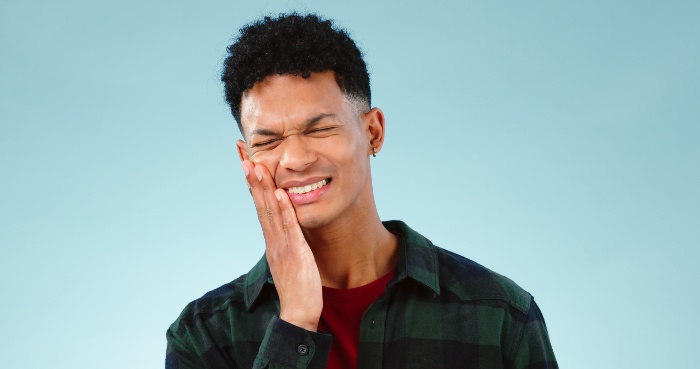 Person holding jaw with tooth pain for emergency dental care in Boise, ID